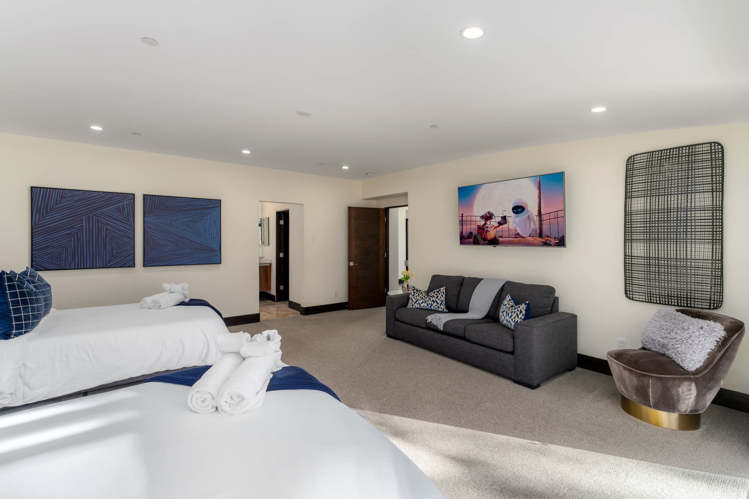 Large light bedroom with beds and a gray sofa