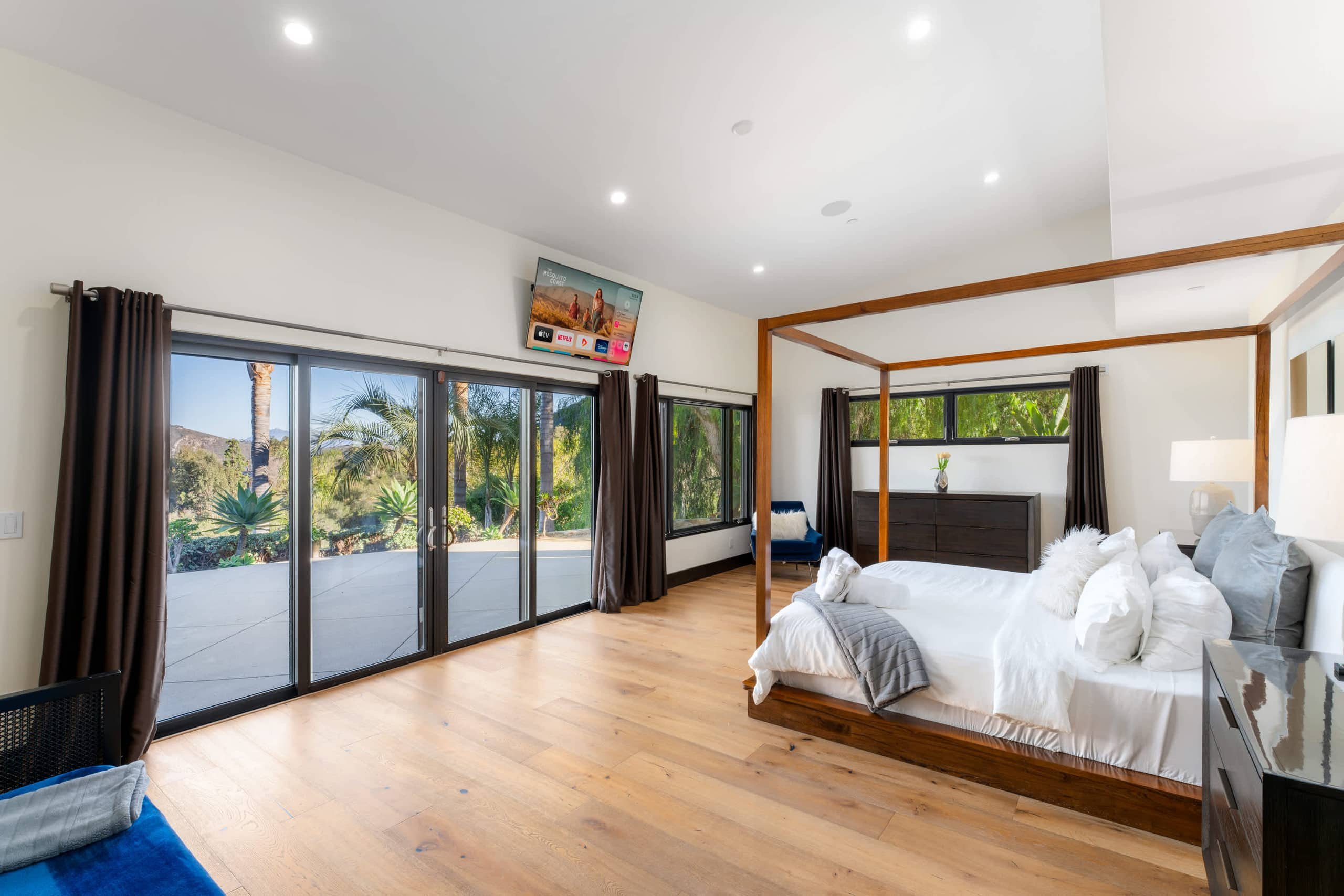Bright bedroom with a four-poster bed, wood floors and glass doors to the garden